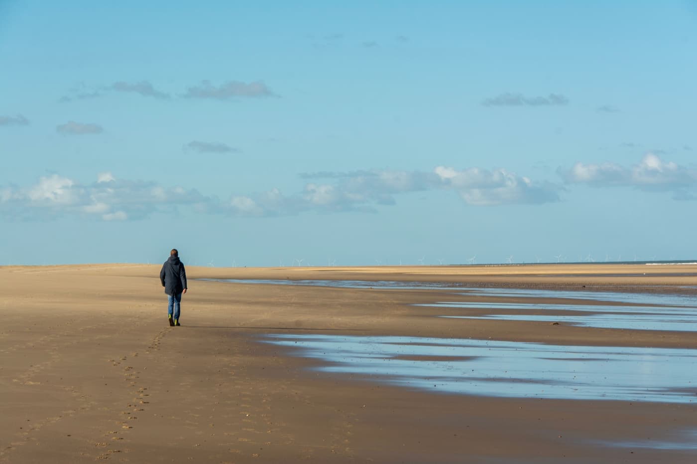 Single figure walking in the distance along a wide empty beach