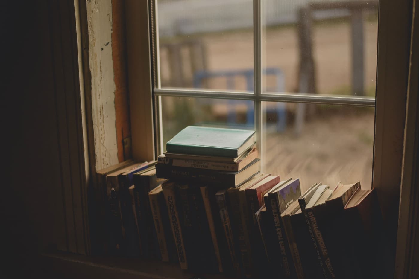 Stack of books beside a window in warm morning light