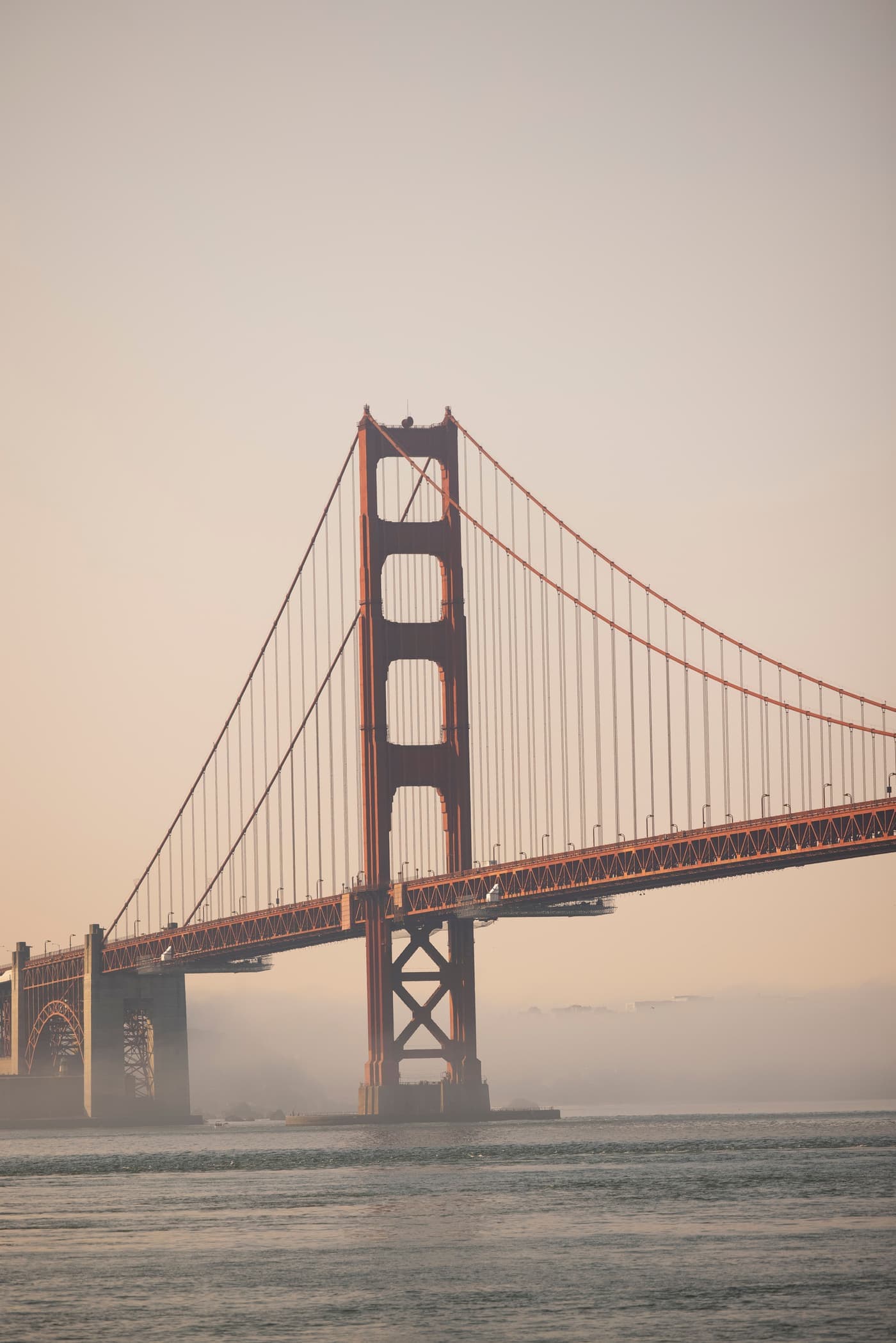 Golden Gate Bridge rising through morning fog at sunrise