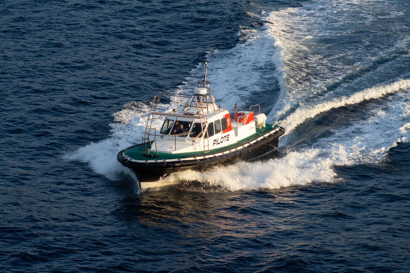 Harbour pilot boat cutting through coastal water at sunset near Marseille