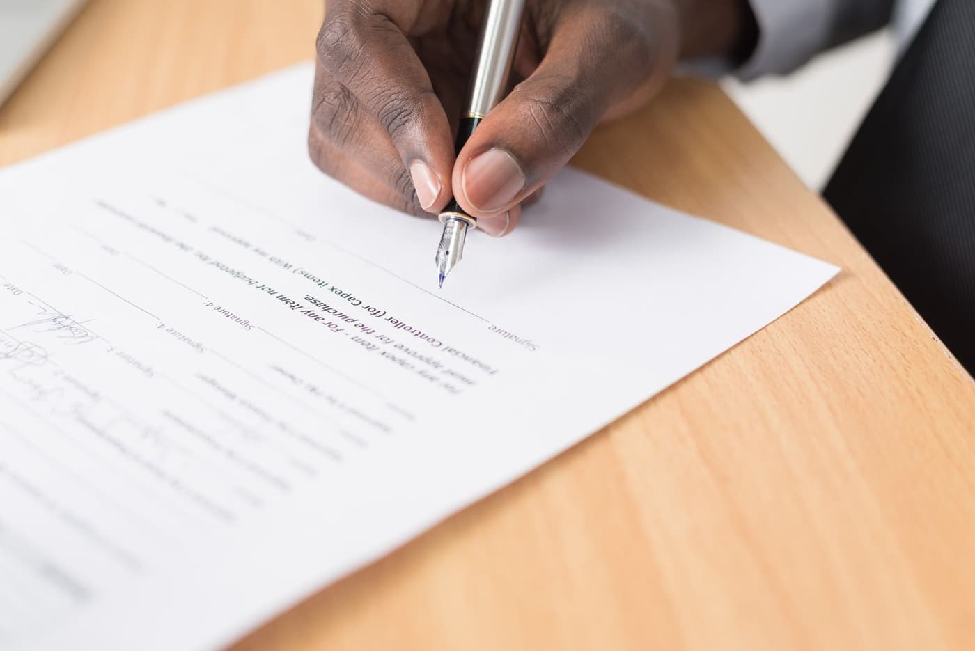 A formal document on a desk with a fountain pen resting on it.
