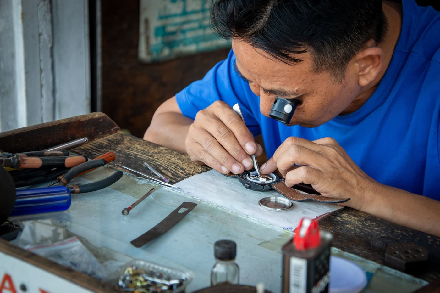 Watchmaker working on a movement at a cluttered workbench