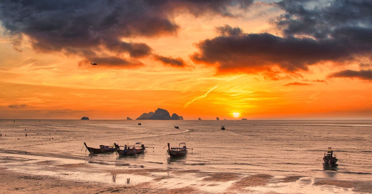A Krabi beach at golden sunset with longtail boats, Thailand