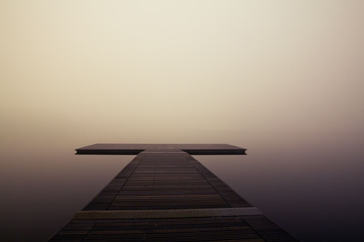 A wooden jetty reaching into a calm sea at dawn