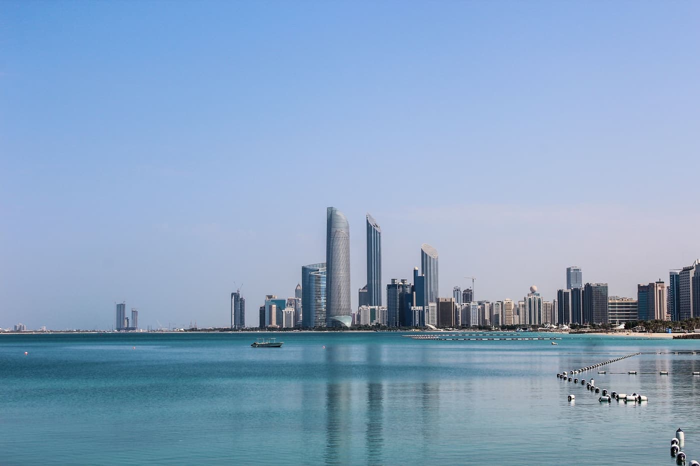 Abu Dhabi skyline reflected in calm Gulf waters on a clear day
