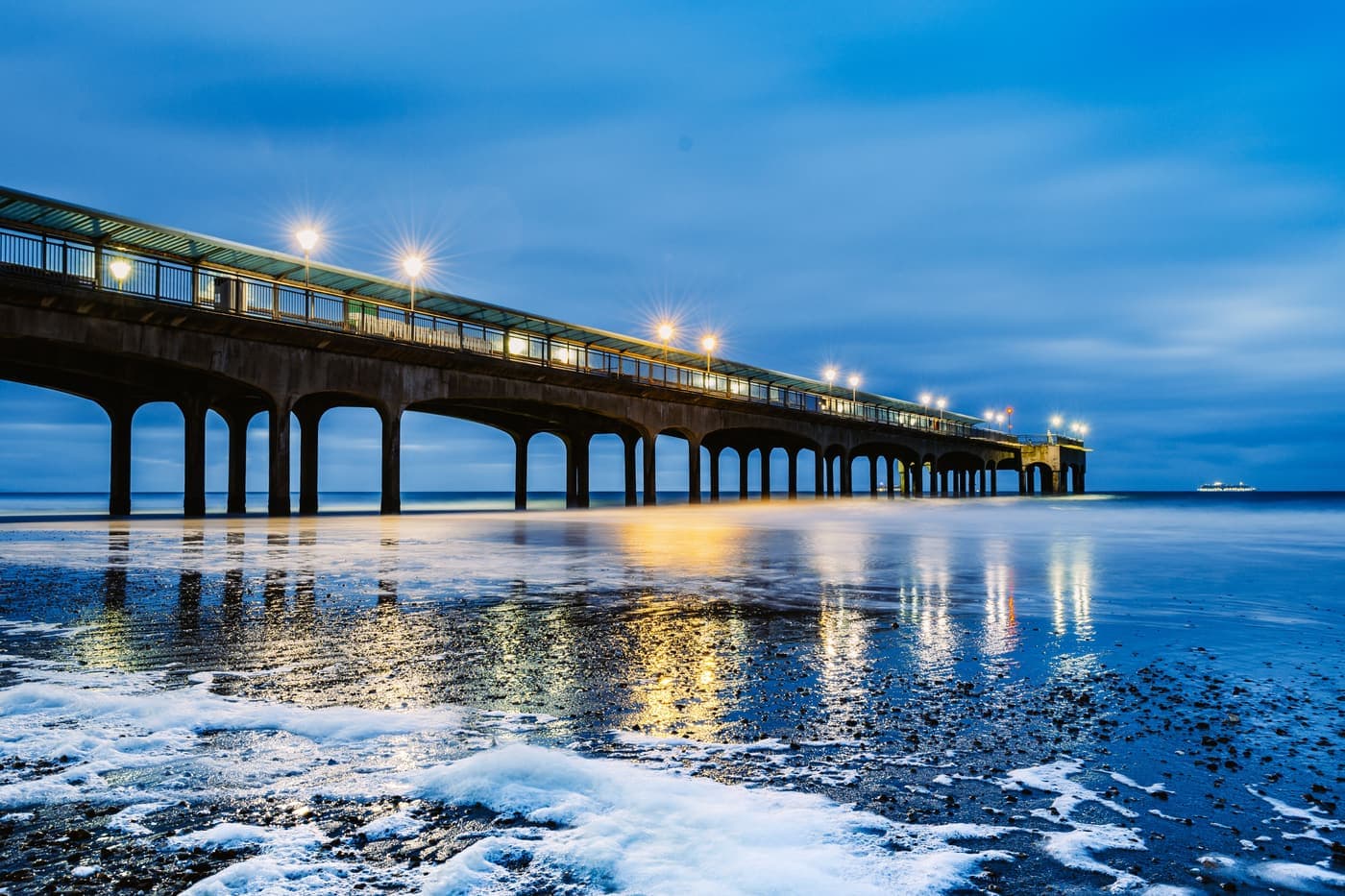Boscombe Pier reflected on wet sand in winter twilight