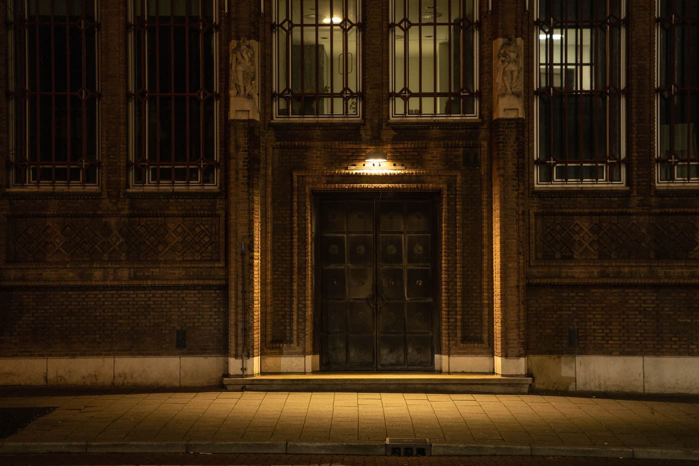 Warmly lit entrance of a historic building with ornate stonework at dusk