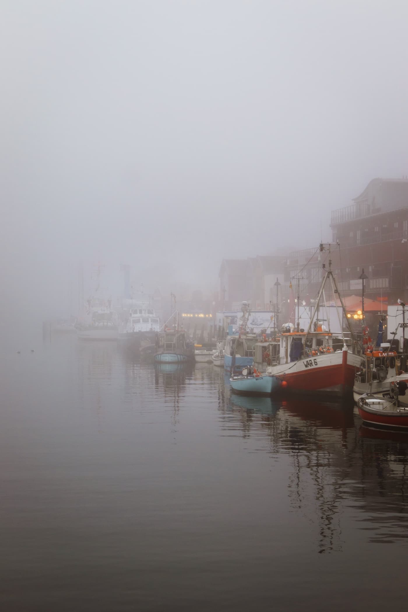 Fishing boats in a misty morning harbour at Rostock