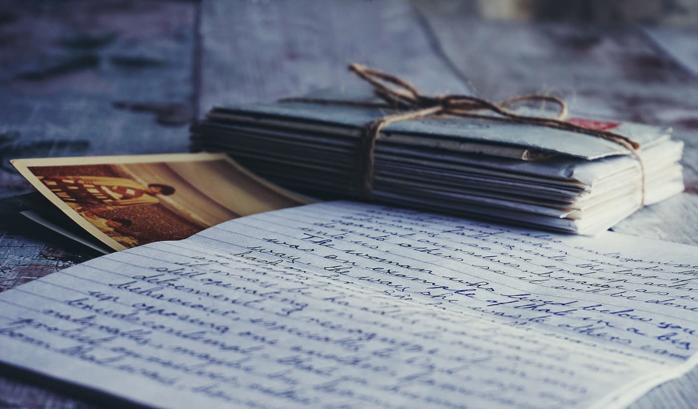 Stack of vintage letters and photographs tied with string on a wooden table