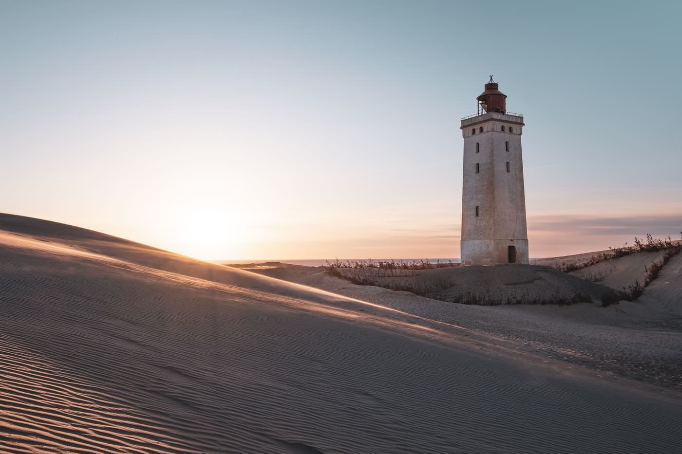 Rubjerg Knude lighthouse rising from sand dunes at sunset, Denmark