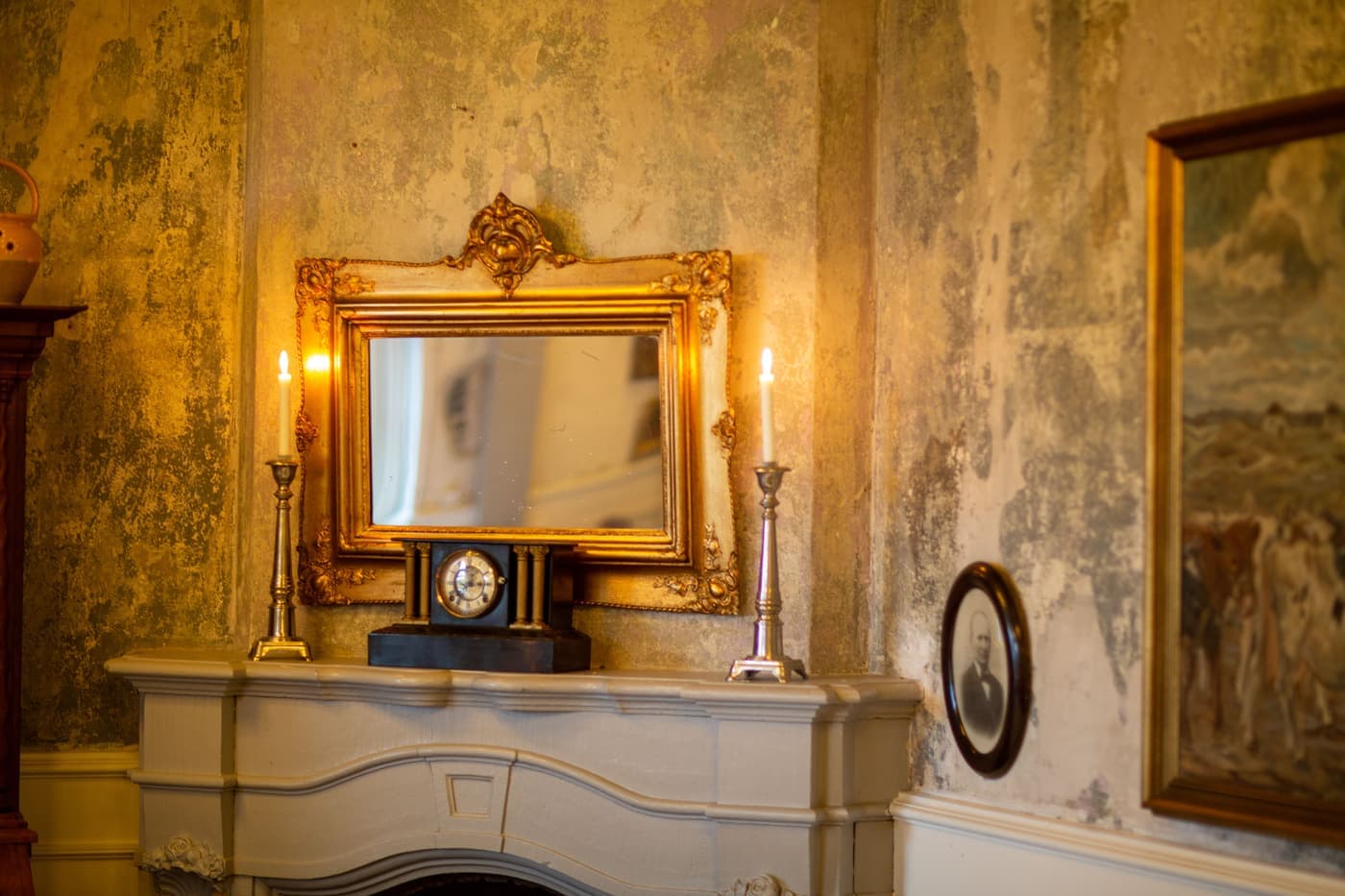 Gilt mirror, candles and inherited ornaments arranged on a mantelpiece