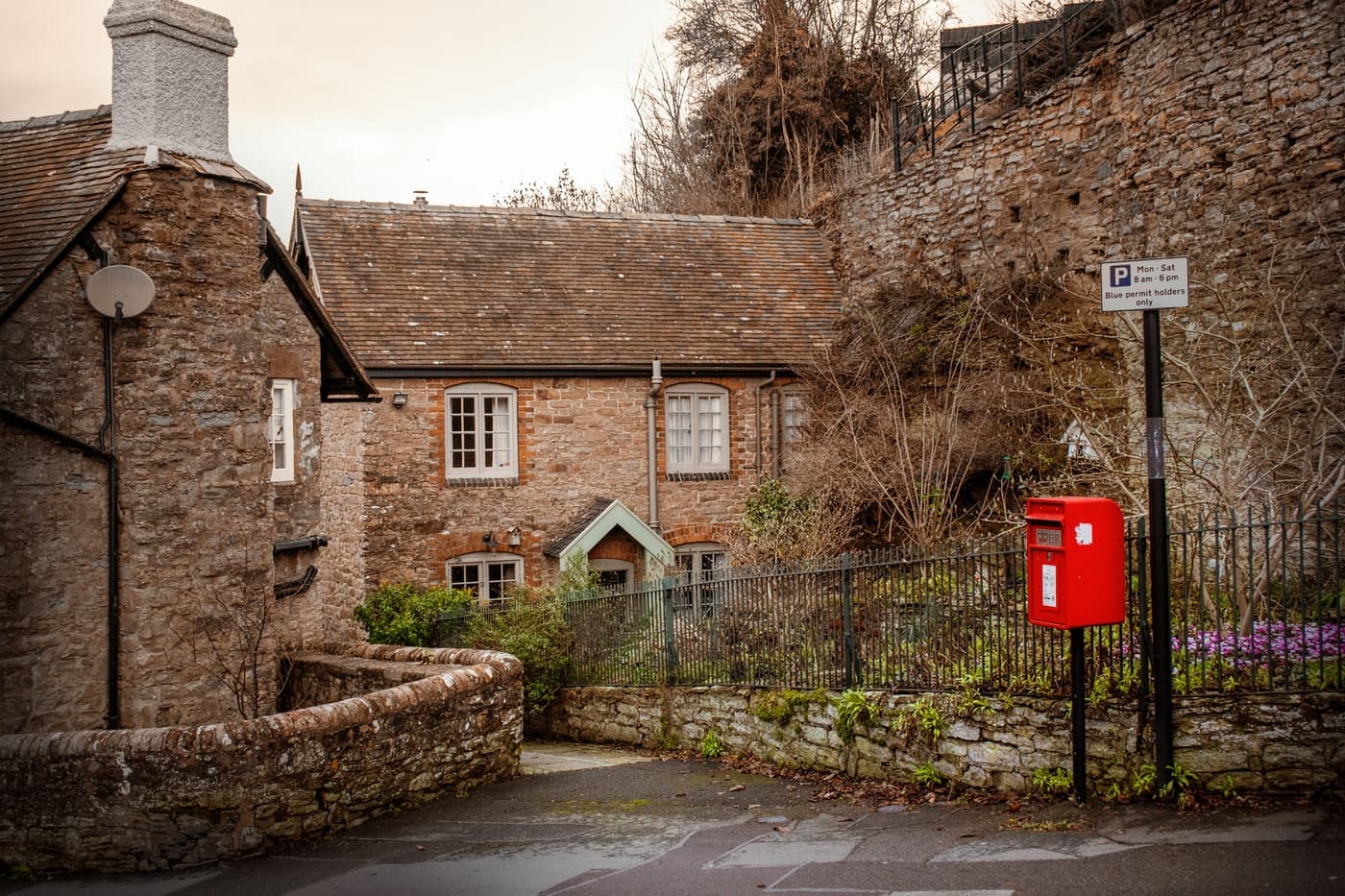 Red postbox beside an English stone cottage in a village lane