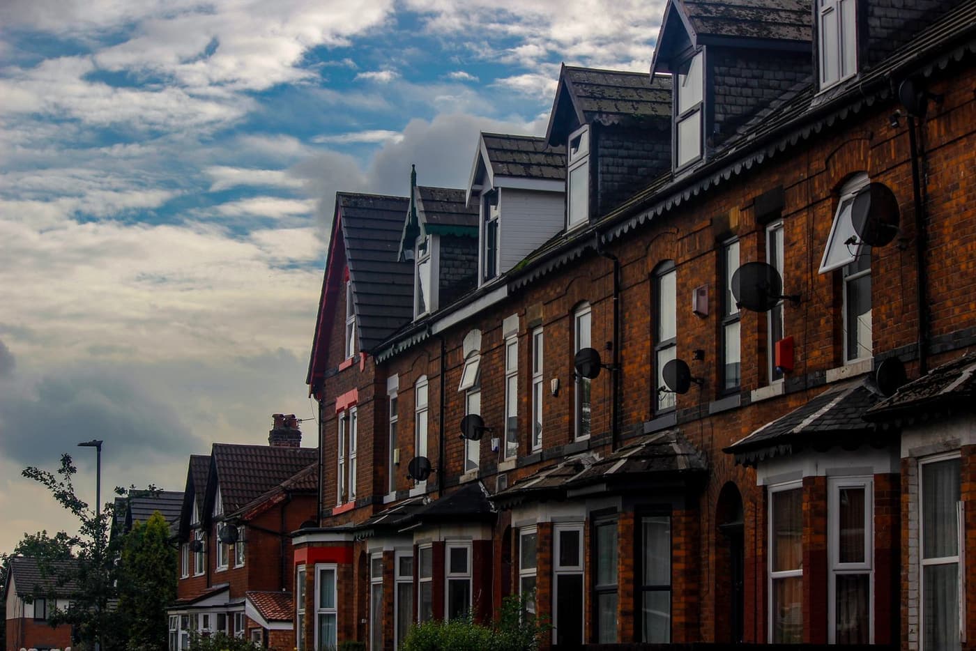 A row of brick terraced houses along a suburban street.