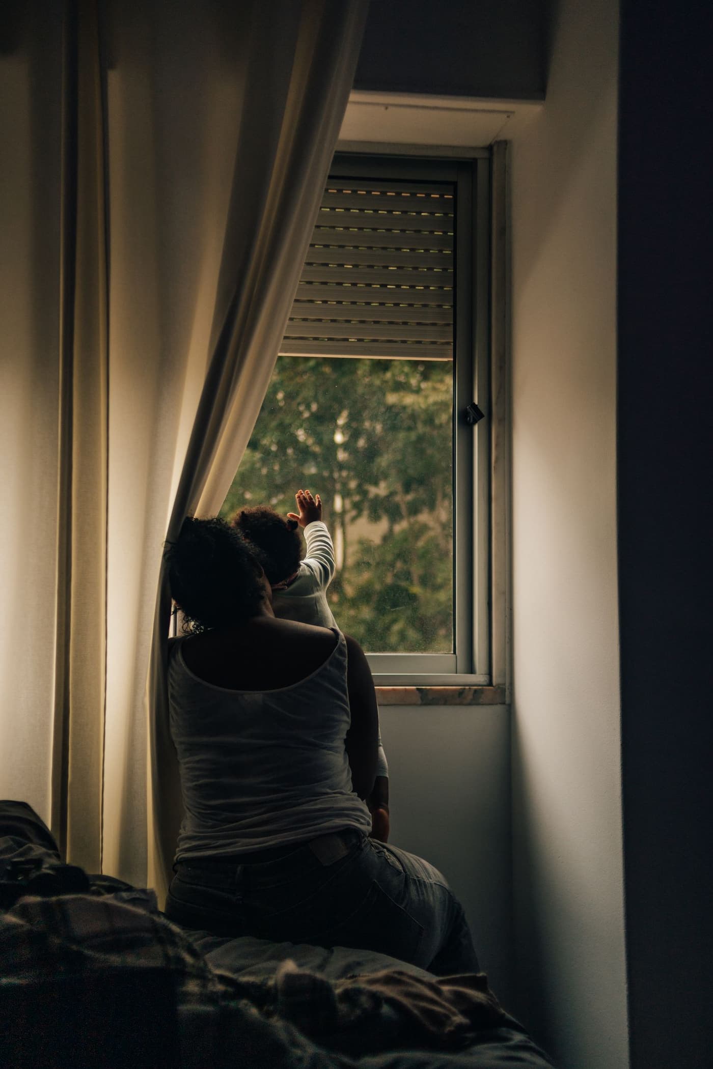 A parent and child at a window, seen against the light.