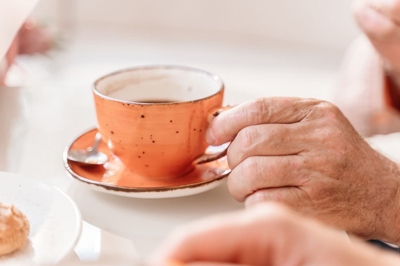 An older hand reaching for a warm cup on the table.