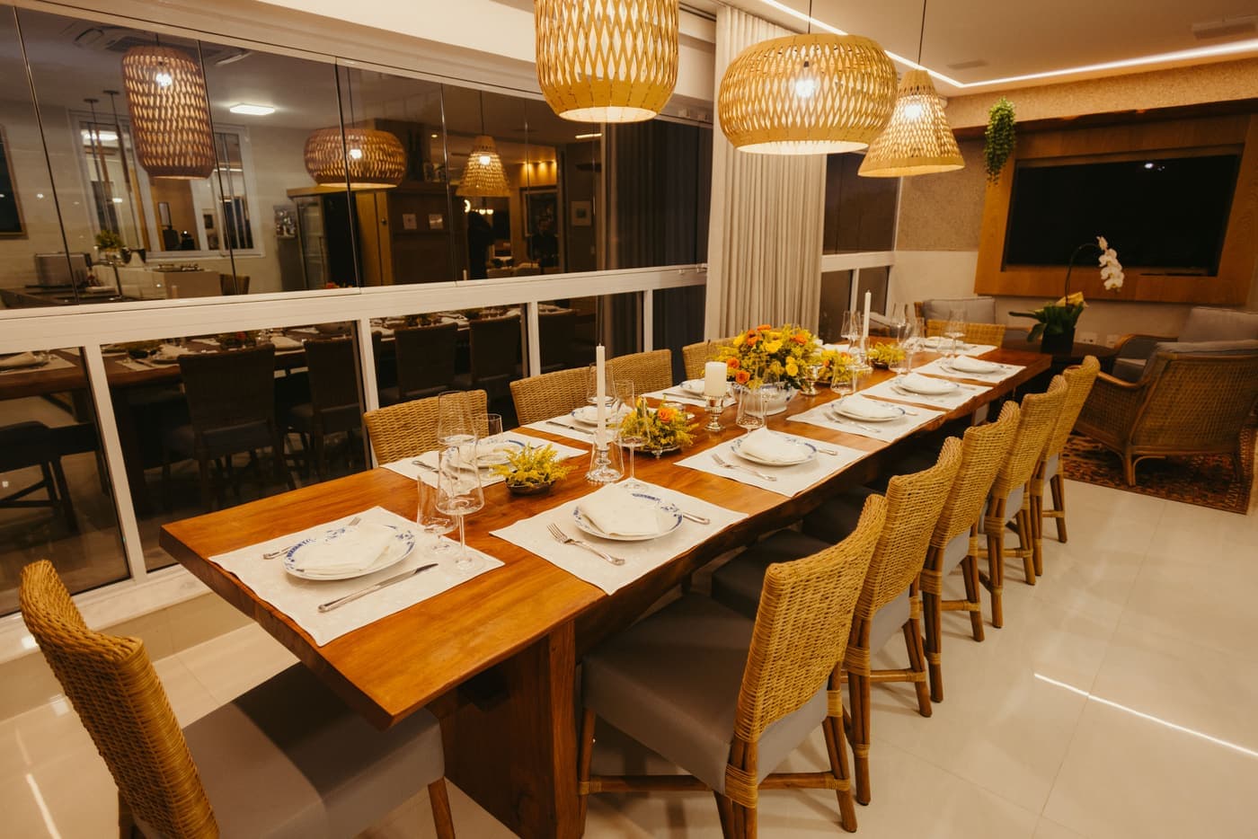 Warm dining room with a wooden table laid for guests under soft lamplight