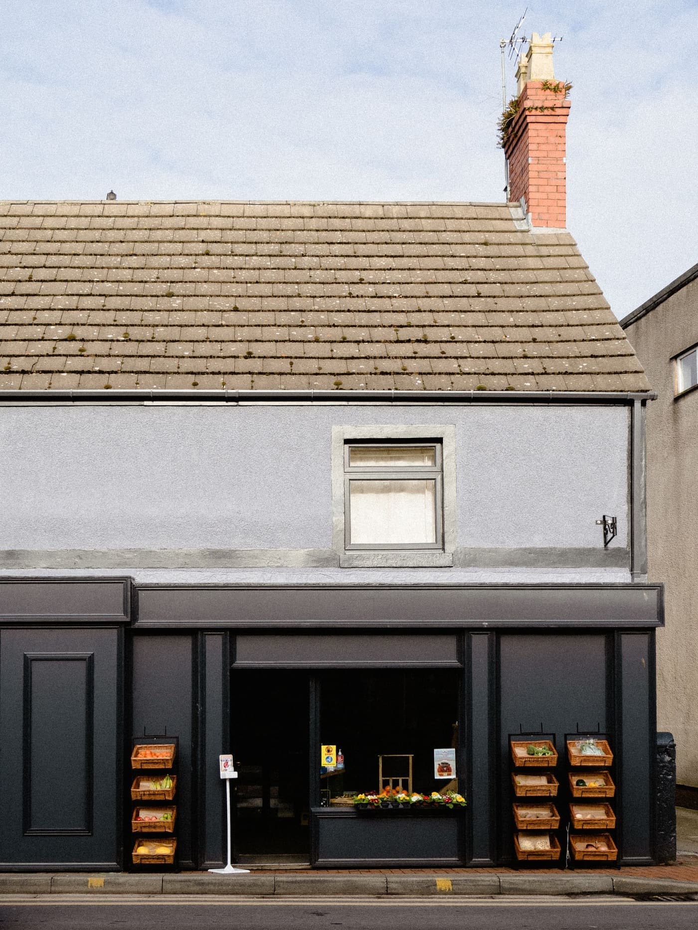 A small neighbourhood grocery shop with produce baskets outside.