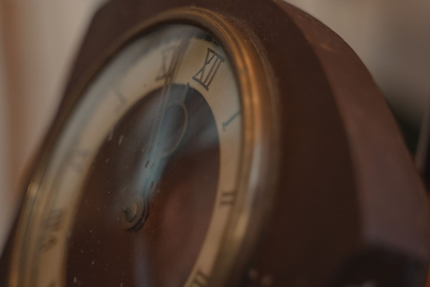 The face of an antique clock with Roman numerals, hands still.