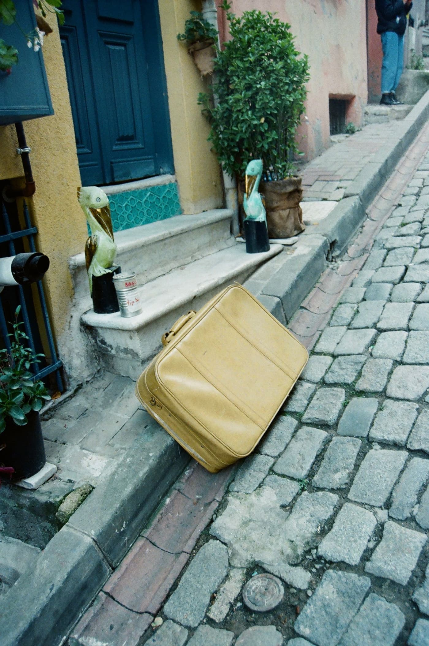 A suitcase standing beside a doorway on a cobbled street.